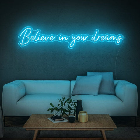 Believe in Your Dreams LED neon sign in blue, mounted on a wall above a modern sofa