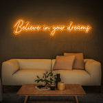 Believe in Your Dreams LED neon sign in orange, lighting up a minimalist modern interior.