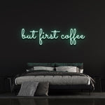 Green "But First Coffee" LED neon sign above a cozy bed setup on a black wall, great decor for coffee lovers and modern spaces.