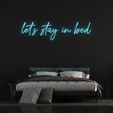Stylish 'Let's Stay in Bed' LED neon sign with clear acrylic backboard for modern bedroom lighting.