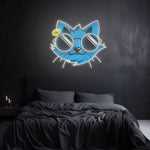 Cool Cat LED Neon Sign glowing above a bed, featuring a stylish blue cat with sunglasses, adding vibrant and modern decor to the wall.

