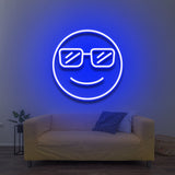 Cool LED Neon Sign featuring a smiling face with sunglasses, glowing blue against a light wall, perfect for modern room decor above a couch.

