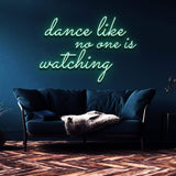 Green neon sign reading "Dance like no one is watching" mounted on a dark blue wall above a modern couch. Ideal for home decor or party lighting.