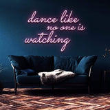Pink neon sign displaying "Dance like no one is watching" installed in a stylish home setting, offering vibrant lighting for any room or celebration.