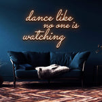 Warm orange neon sign reading 'Dance like no one is watching' above a contemporary blue sofa in an elegant interior setting.
