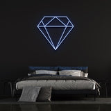 Blue diamond-shaped LED neon sign on black wall in trendy bedroom with bed and pillows.
