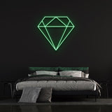 Green diamond-shaped LED neon sign on black wall in cozy bedroom with bed and pillows.