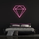 Pink diamond-shaped LED neon sign on black wall in chic bedroom with bed and pillows.