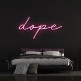 Dope LED neon sign in pink color mounted on a black wall above a modern bed, ideal for trendy bedroom wall decor.