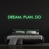 Green "Dream, Plan, Do" LED neon sign in an elegant bedroom arrangement.