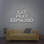 Minimalist Eat Pray Espresso LED neon sign in white color above a yellow sofa for modern interiors.