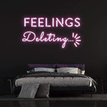 Pink "Feelings Deleting" neon sign mounted on a black wall, enhancing the aesthetic of a contemporary bedroom setting.