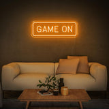 orange GAME ON LED neon sign with modern white couch and a coffee table in the room.