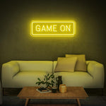 Yellow GAME ON LED neon sign with modern white couch and a coffee table in the room.