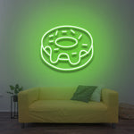 Green donut LED neon sign as modern wall decor above a yellow couch with green accents.
