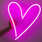 Heart neon sign in vibrant pink, an eye-catching illuminated decor piece adding warmth and charm to any home or office space.