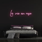 La Vie en Rose LED neon sign with pink glow, elegant cursive font perfect for home décor or special events.