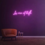 La Vue Est Belle LED Neon Sign glowing in pink, ideal for creating a playful and inviting atmosphere in any space.