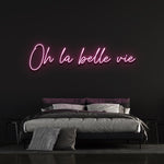 Charming pink 'Oh la Belle Vie' LED neon sign, ideal for creating a warm and inviting ambiance in your home or office, celebrating the simple joys of life.