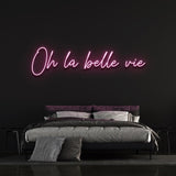 Charming pink 'Oh la Belle Vie' LED neon sign, ideal for creating a warm and inviting ambiance in your home or office, celebrating the simple joys of life.