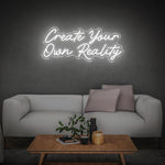 White neon sign displaying "Create Your Own Reality" above a minimalist sofa, adding modern elegance to room decor.