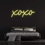 XOXO LED neon sign in vibrant yellow light, perfect for bedroom decor and romantic ambiance.